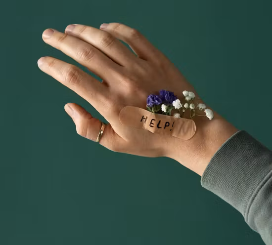 A hand with a band aid with the word 'help' written and flowers under it